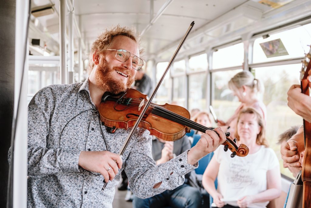 Violinist Lukas Bergmann-Gabel von Crepes Sucette spielt bei einem Straßenbahnkonzert live zwischen den Gästen.